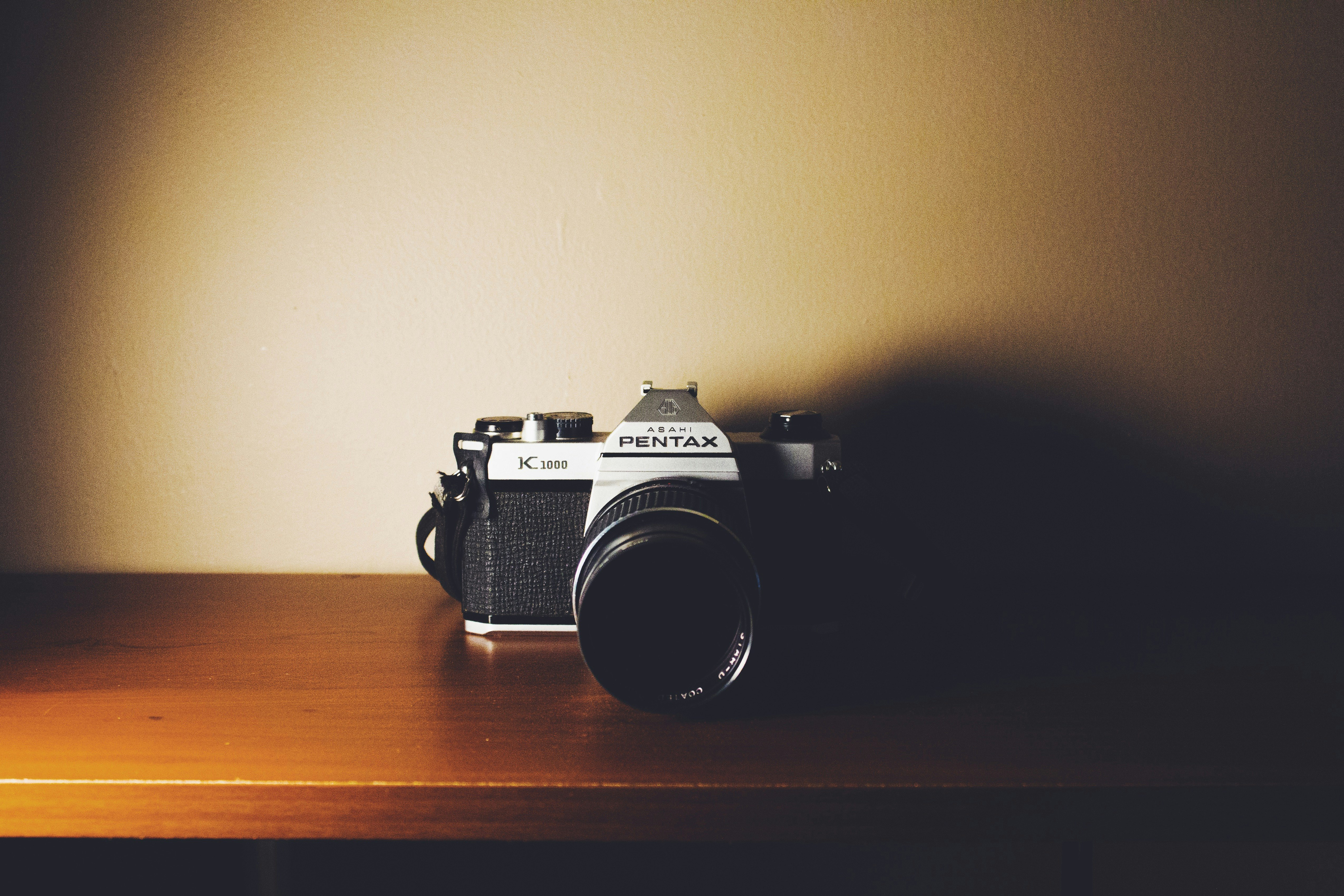 black and gray Pentax digital camera on wooden surface